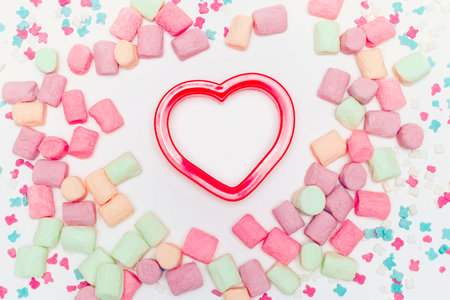 Valentine's Day red heart in the middle, colorful sweets scattered around. Flat lay. Copy space.