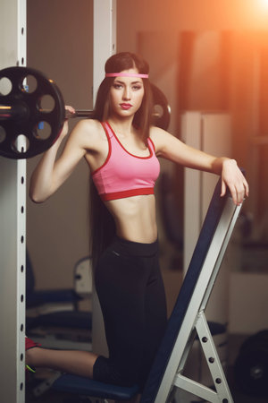 Sexy brunette with long hair and sporting appearance posing in the gym. Young fitness woman in pink t-shirt trainers at the gym.の写真素材