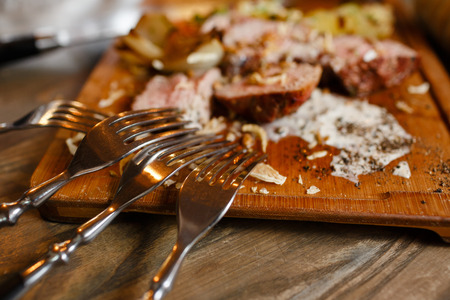 Fork close up lying on a wooden board with juicy roasted meatの写真素材