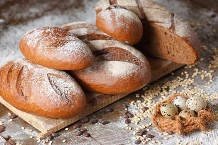 Variety of rye bread on a wooden background with flour, grain and quail eggsの写真素材