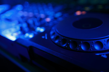 DJ mixer with light colored spotlights discos, shallow depth of field and beautiful swirling bokehの写真素材