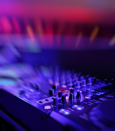 DJ mixer with light colored spotlights discos, shallow depth of field and beautiful swirling bokehの写真素材