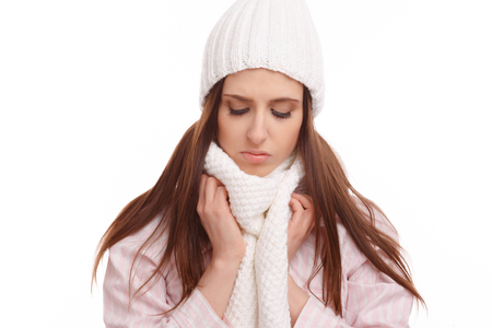 Young woman sick and closed with a scarf on white background. Sneezing into Tissue.の写真素材