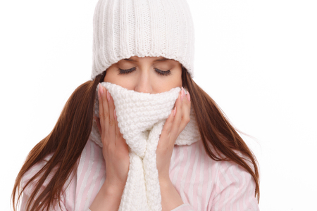 Young woman sick and closed with a scarf on white background. Sneezing into Tissue.の写真素材