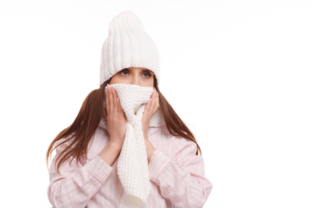 Young woman sick and closed with a scarf on white background. Sneezing into Tissue.の写真素材