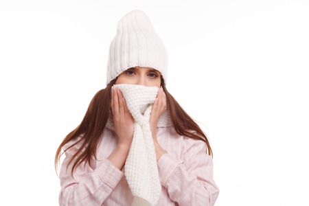 Young woman sick and closed with a scarf on white background. Sneezing into Tissue.の写真素材