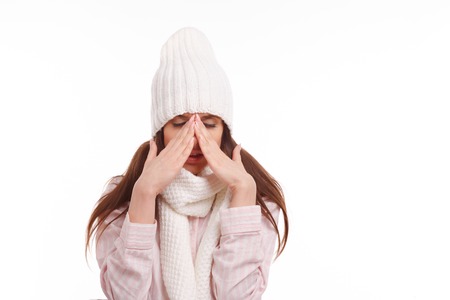 Young woman sick and closed with a scarf on white background. Sneezing into Tissue.の写真素材