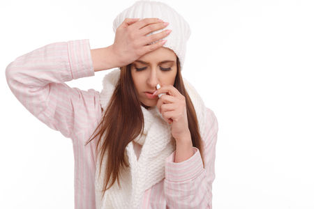 Sick young woman in pajamas scarf and hat use nasal spray. Woman applies nasal spray isolated. Sick Woman.Flu.Woman Caught Cold.の写真素材