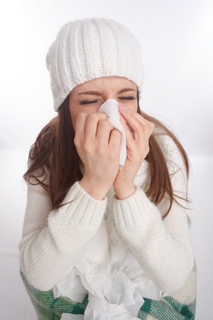 Sick young woman in pajamas scarf and hat coughing and blowing. Desperate and sick. Top viewの写真素材
