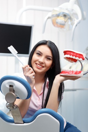 Beautiful young woman explains to dentures how to properly care for your teethの写真素材