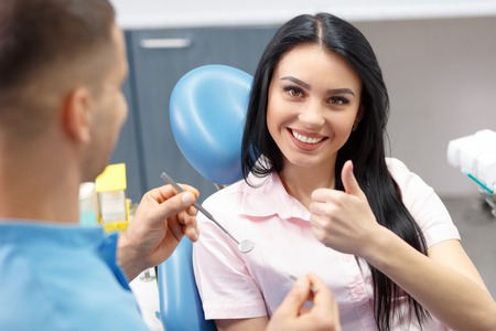 Pretty woman patient shows Like in the dental office. People, medicine, stomatology and health care conceptの写真素材