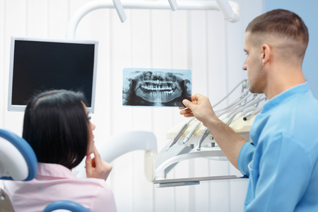 Male dentist showing x-ray of the patient in the dental clinicの写真素材