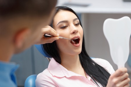 Beautiful girl smiles and looks in the mirror dental clinicの写真素材