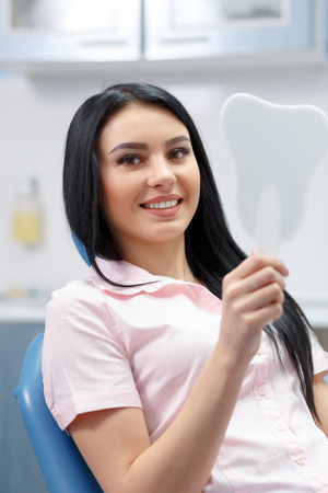 Beautiful girl smiles and looks in the mirror dental clinicの写真素材