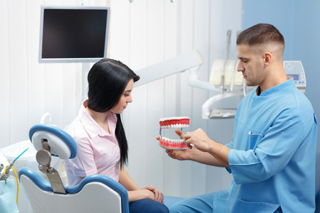 Male dentist explaining a female patient denture work in dental clinicの写真素材