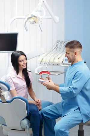 Male dentist explaining a female patient denture work in dental clinicの写真素材
