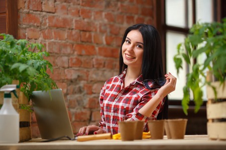 Excited every day. Shot of a cheerful female gardener smiling using a laptop looking to the camera.の写真素材