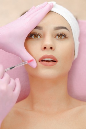 Beautiful woman gets injection in her lips.の写真素材