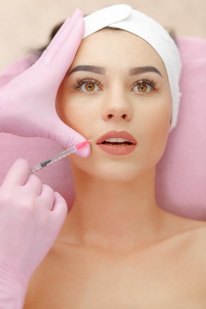 Beautiful woman gets injection in her lips.の写真素材