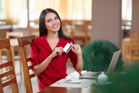 Business woman holding credit card and looking at the camera. Business woman shopping online. Business woman pays for a purchase with credit card. Purchase on the Internet. Buy online. Shopping onlineの写真素材