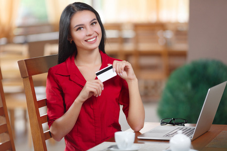 Business woman holding credit card and looking at the camera. Business woman shopping online. Business woman pays for a purchase with credit card. Purchase on the Internet. Buy online. Shopping onlineの写真素材