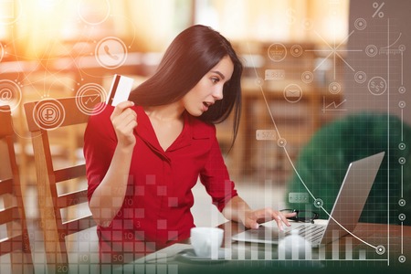 Angered woman holding credit card and looks in laptop screen. Purchase on the Internet. Buy and shopping online. Business infographicの写真素材