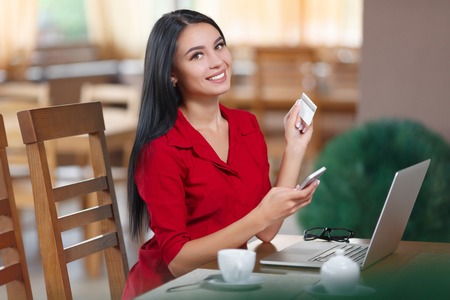 Young business woman holding mobile phone and credit card. Woman pays for a purchase with credit card. Purchase online. Shopping onlineの写真素材