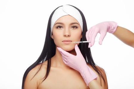 Young woman gets a injection in her lips. Close-up woman hyaluronic acid injection in lips. Injections of skin rejuvenation. Cosmetic procedures, injections and hyaluronic acid.の写真素材