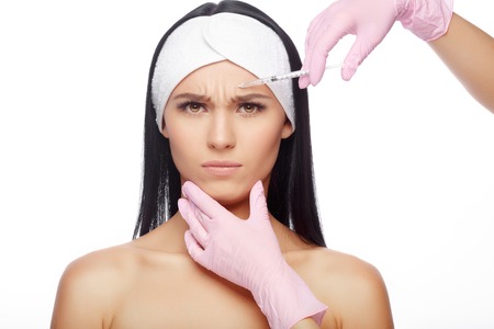 Astonished woman getting lifting injection in cheekbones. Close-up woman hyaluronic acid injection. Injections of skin rejuvenation. Cosmetic procedures, injections, hyaluronic acid.の写真素材