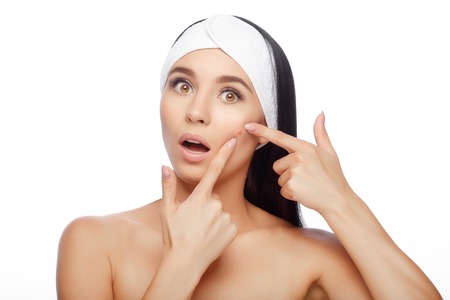 Shocked Woman Looking At Pimple On Forehead. Young Woman Squeezing her Pimple, Removing Pimple from her Face. Woman Skin Care Conceptの写真素材