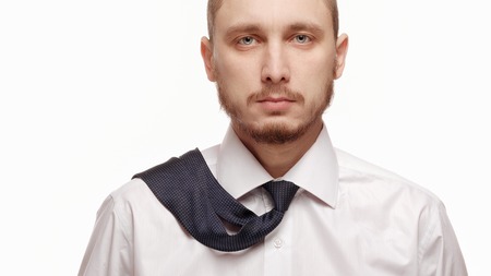 Portrait of young man in white shirt on white background. Man with beard in white shirt and loosened his tieの写真素材