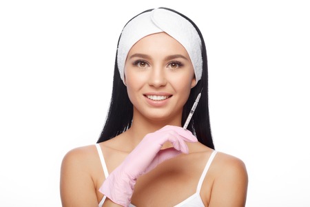 Beautiful young woman holding a syringe with an injection, isolated on white background. Cosmetic procedures, injections, hyaluronic acid.の写真素材