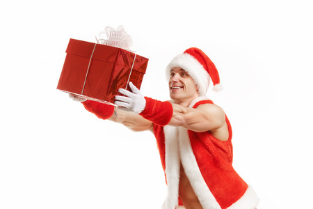 Bodybuilder Santa Claus gives a gift in red box. Cheerful fitness Santa holding a red box. Muscular Santa Claus isolated over white background.の写真素材