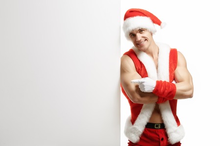 Fitness Santa Claus with a banner sales. Joyful Santa Kraus points to the banner sales. Merry Fitness Santa isolated on white background. Christmas banner sales. Christmas sale.の写真素材