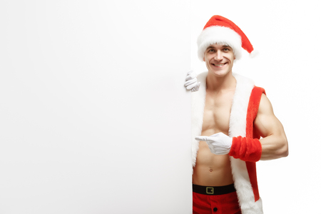 Fitness Santa Claus with a banner sales. Joyful santa claus points to the banner sales. Merry Fitness Santa isolated on white background. Christmas banner sales. Christmas sale.の写真素材