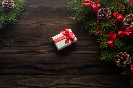 Christmas wooden background with Christmas tree and red decoration. Christmas background cardboard box with a red bow. A Christmas gift. Gift on Valentine's Day. Christmas white cardboard box with a red bowの写真素材