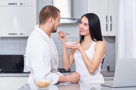 Wife feeding her husband of oat flakes.の写真素材