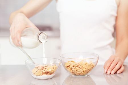 Female pouring milk in plate with oak flakes.の写真素材