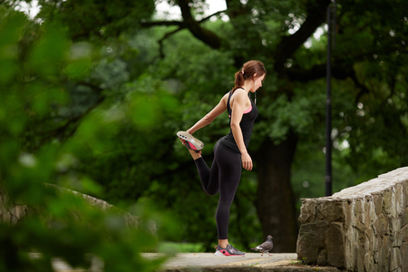 Sportswoman stretching in summer parkの写真素材
