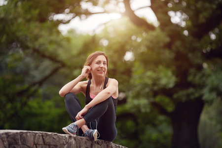 Cheerful sportswoman with headphones in parkの写真素材