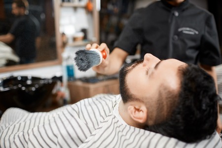 Hairstylist combing out and cutting bread for brunet client.の写真素材