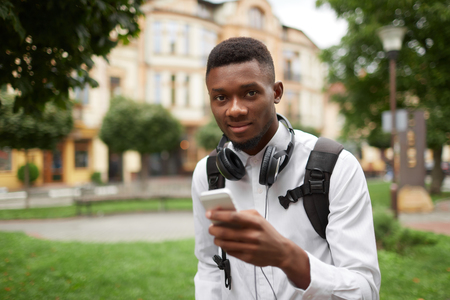 African student chatting, writing message with smart phone.の写真素材