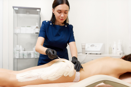 Attractive woman having white mask on her body in beauty salon.の写真素材