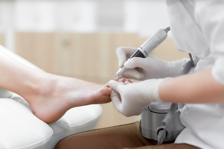 Doctor in gloves making procedure for foot with special equipment.