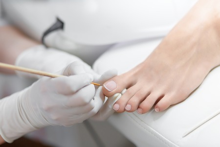 Specialist in beauty salon making french pedicure for female client.の写真素材