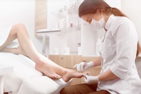 Brunette female podiatrist making polish and cleaning procedureの写真素材