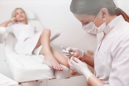 Podiatrist doctor caring about client foot with special iron tooの写真素材