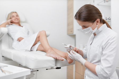 Podiatrist doctor cleaning foot from callus.の写真素材