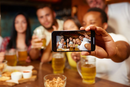 Group of funny friends taking self portrait in bar.の写真素材
