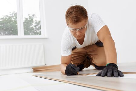 Handyman installing new laminated wooden floorの写真素材